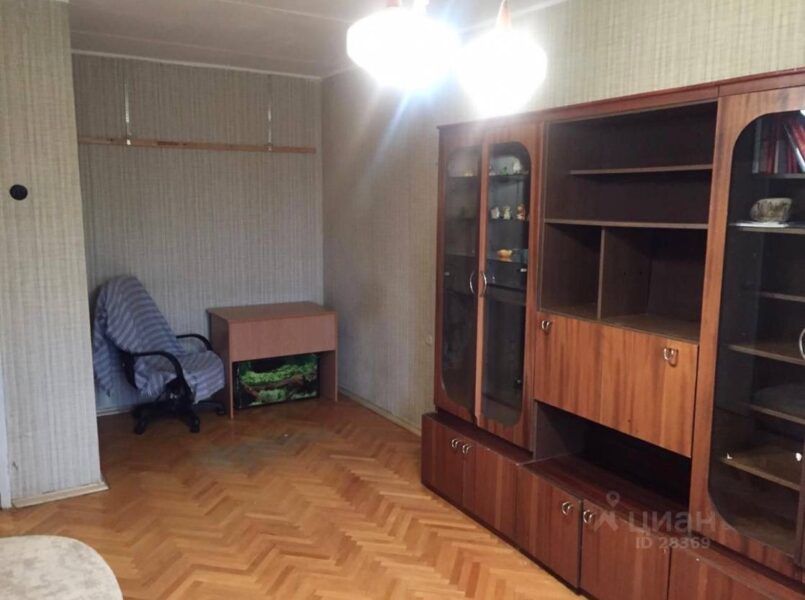 комната с мебельной стеной,голубое кресло рядом со стеной , фанерная тумба и паркет