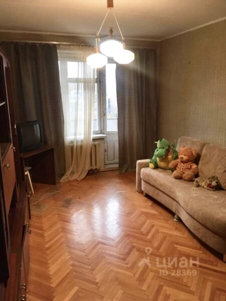 Комната с диваном и паркетом ,черный телевизор на тумбе,темные шторы